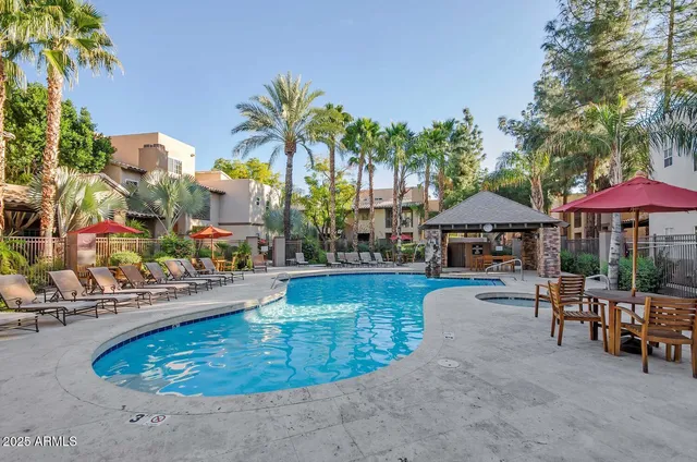 a view of a swimming pool with a table and chairs under an umbrella