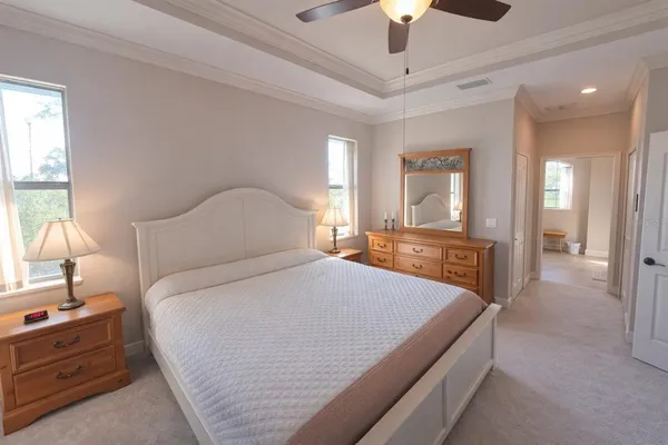 a bedroom with a large bed and a chandelier fan