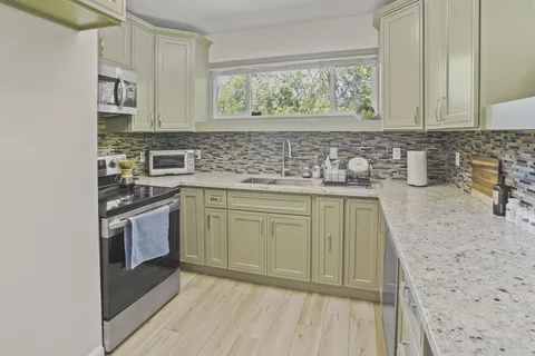 a kitchen with stainless steel appliances granite countertop a sink stove and cabinets