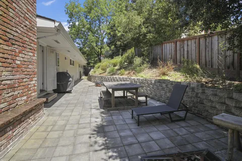 a view of backyard with a table and chairs and a large tree