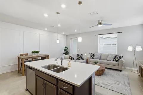 a living room with furniture kitchen view and a window
