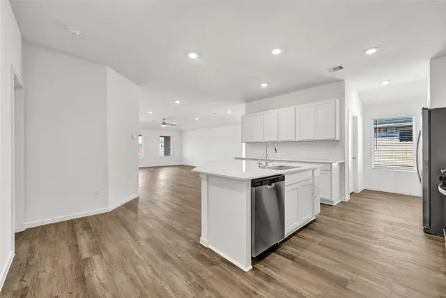 a kitchen with stainless steel appliances granite countertop a stove top oven a sink and white cabinets