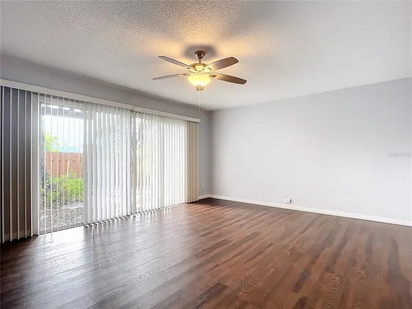 an empty room with wooden floor fan and windows