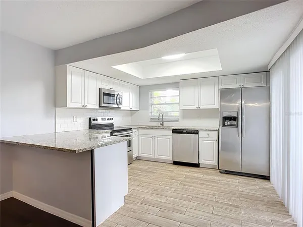 a kitchen with granite countertop a refrigerator stove top oven and sink