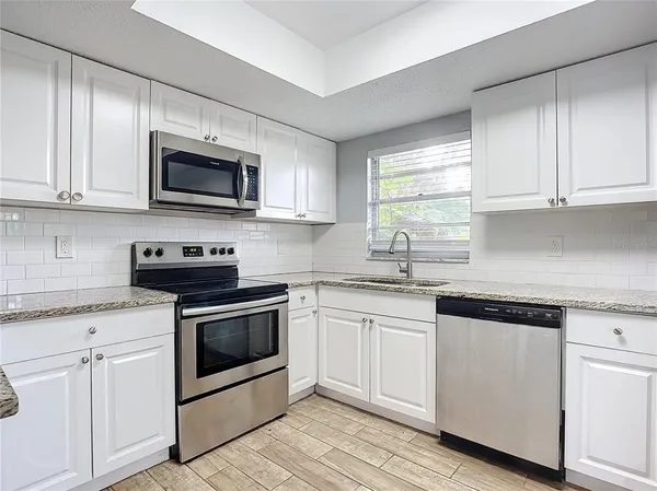 a kitchen with white cabinets appliances and a sink