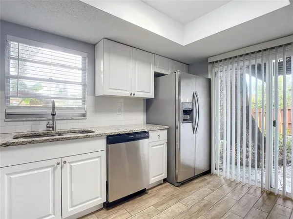 a kitchen with stainless steel appliances granite countertop a sink and a refrigerator
