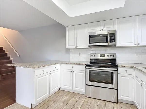 a kitchen with cabinets stainless steel appliances and wooden floor