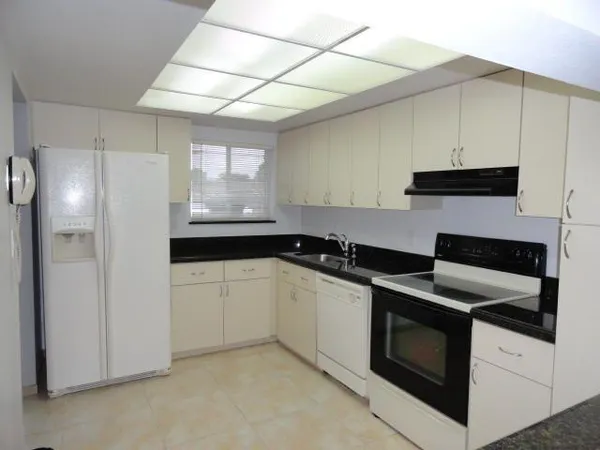 a kitchen with granite countertop white cabinets and white appliances