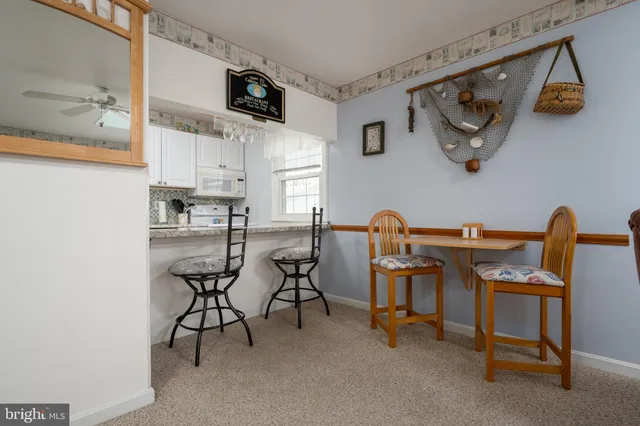 a view of kitchen with stainless steel appliances granite countertop dining table chairs and a wooden floor
