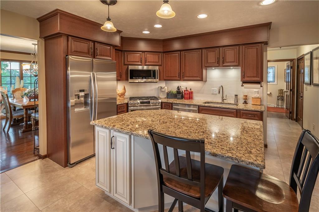 106 Roundtable Drive McMurray, PA 15317 - Photo 8 of 25 a kitchen with stainless steel appliances granite countertop a refrigerator a stove a sink a dining table and chairs with wooden floor