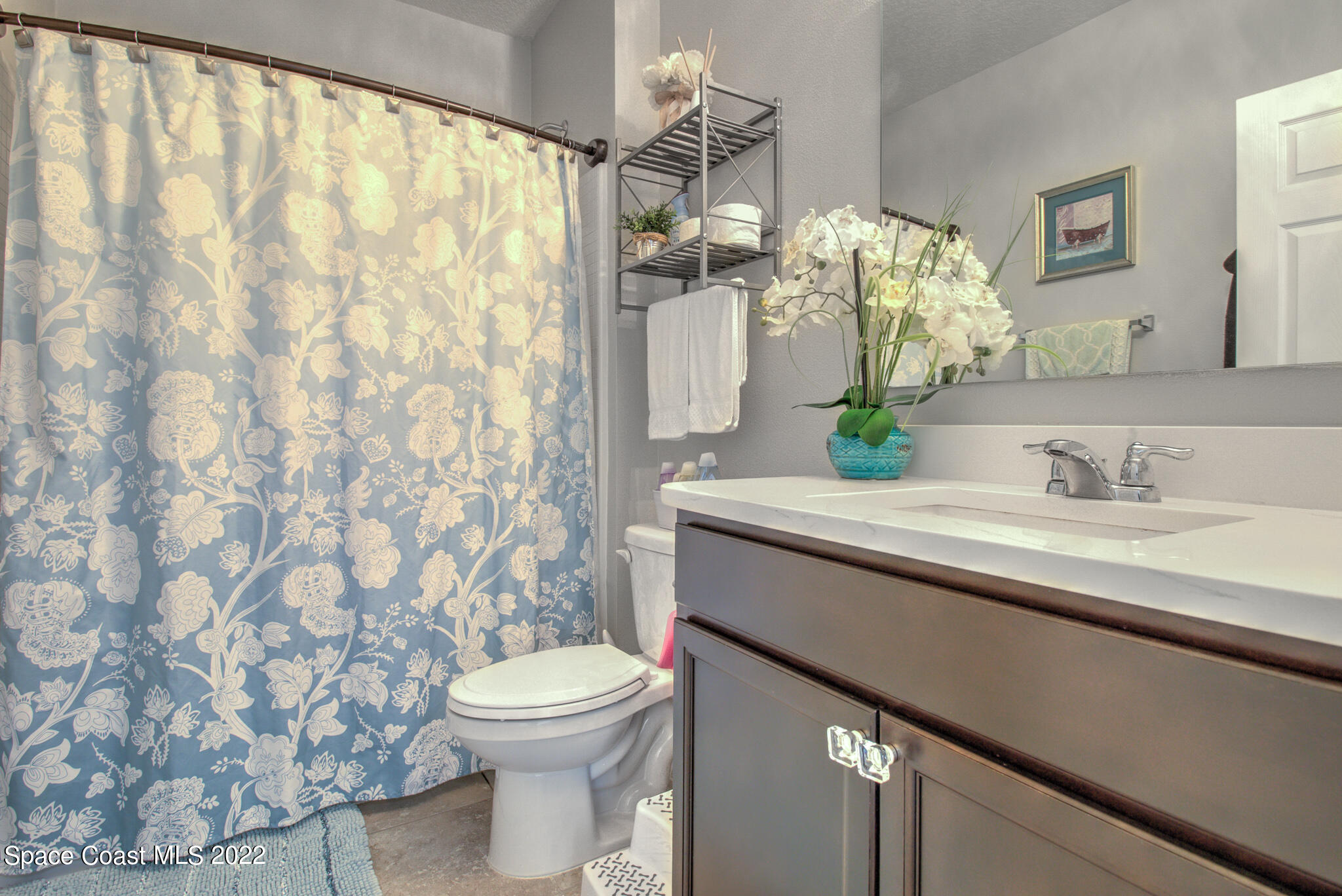 975 Newton Circle Rockledge, FL 32955 - Photo 22 of 30 a bathroom with a granite countertop sink a toilet and a mirror