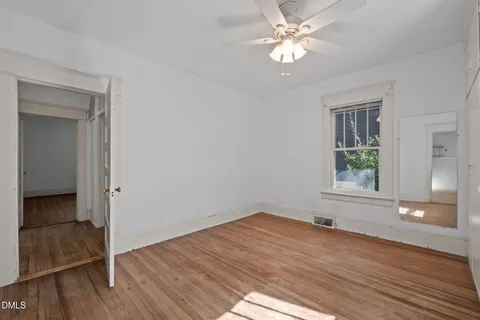 a view of empty room with wooden floor and fan