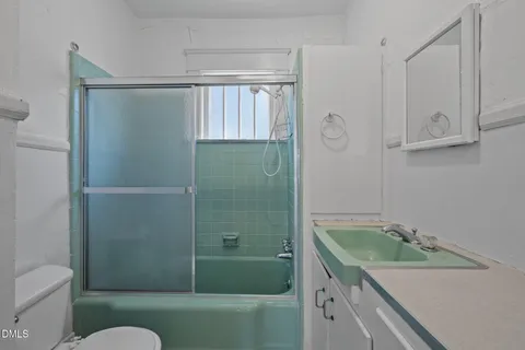 a bathroom with a granite countertop sink a toilet and shower