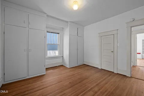 a view of empty room with wooden floor and window