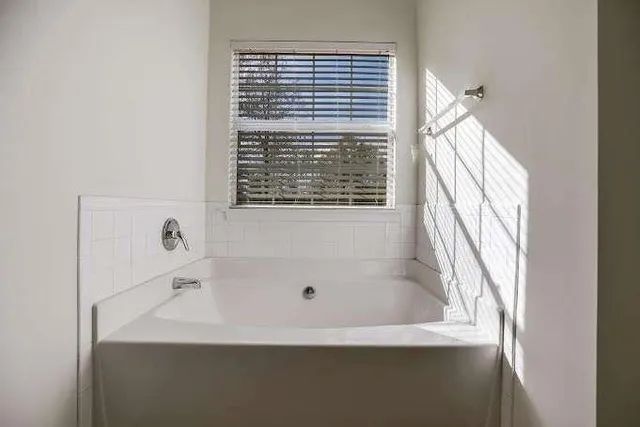 a bathroom with bathtub and window