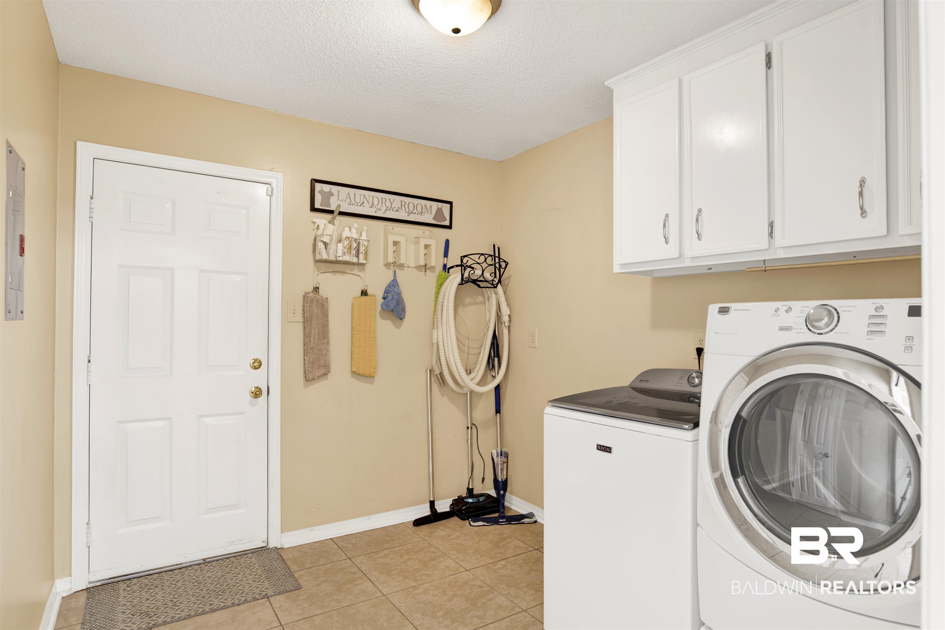 7431 Summer Court Mobile, AL 36695 - Photo 18 of 37 Laundry room featuring cabinet space, washing machine and clothes dryer, baseboards, light tile patterned flooring, and a textured ceiling