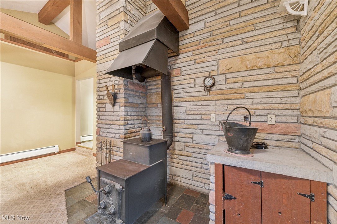 6326 Murray Ridge Road Elyria, OH 44035 - Photo 6 of 49 Kitchen featuring beam ceiling, a wood stove, baseboard heating, and range hood