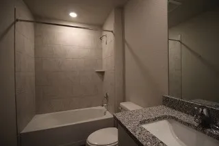 a bathroom with a granite countertop sink toilet and shower