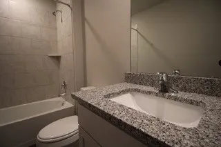 a bathroom with a granite countertop bathtub shower sink and toilet