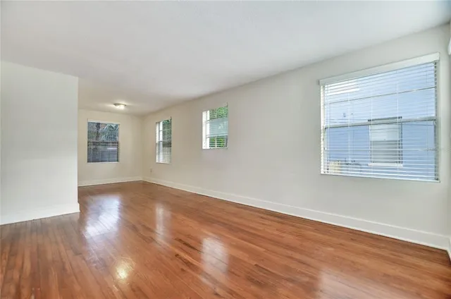 a view of an empty room with wooden floor and a window