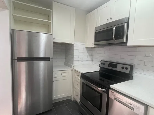 a kitchen with stainless steel appliances granite countertop white cabinets a stove a sink and dishwasher