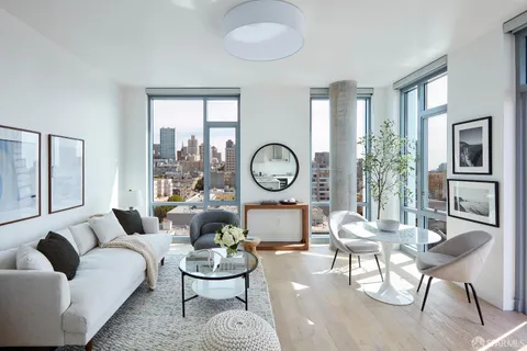 a living room with furniture a rug potted plant and a large window