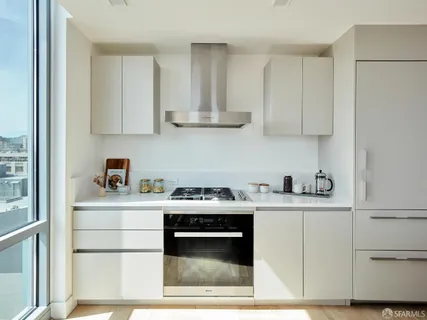 a kitchen with stainless steel appliances granite countertop a stove a sink dishwasher and white cabinets with wooden floor