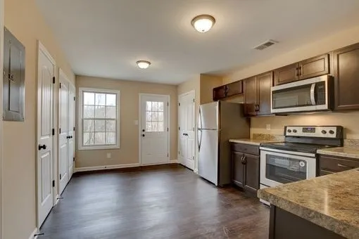 a kitchen with stainless steel appliances granite countertop a refrigerator oven a sink dishwasher and wooden cabinets with wooden floor