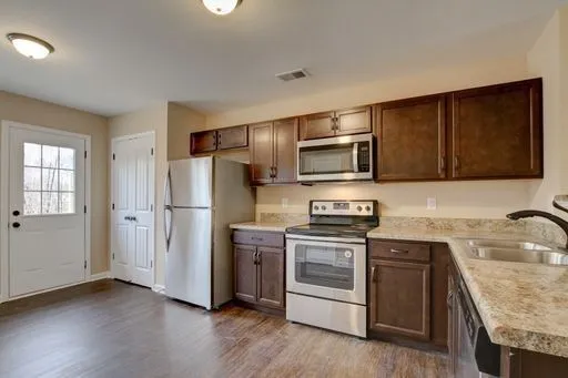 a kitchen with stainless steel appliances granite countertop a refrigerator stove and sink