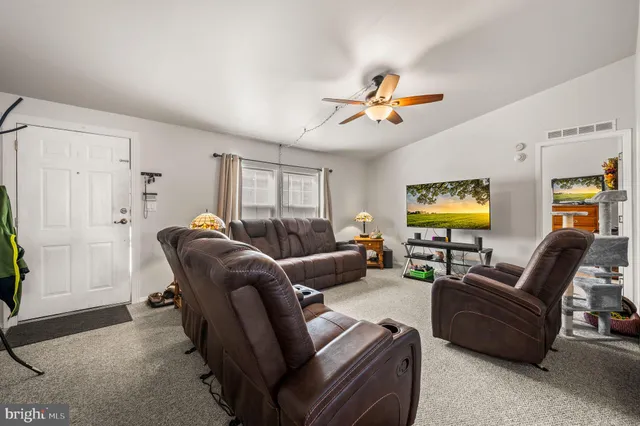 a living room with furniture a ceiling fan and a window