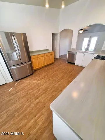 a view of a refrigerator in kitchen and an empty room