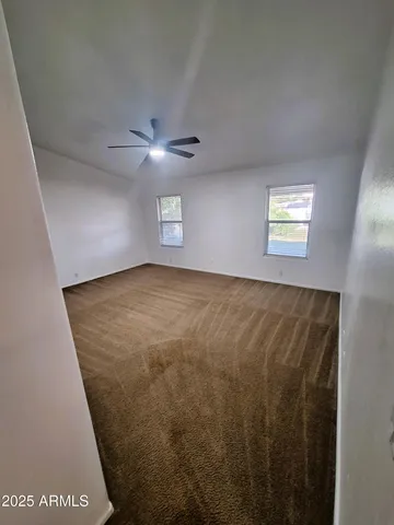 an empty room with a ceiling fan and a window