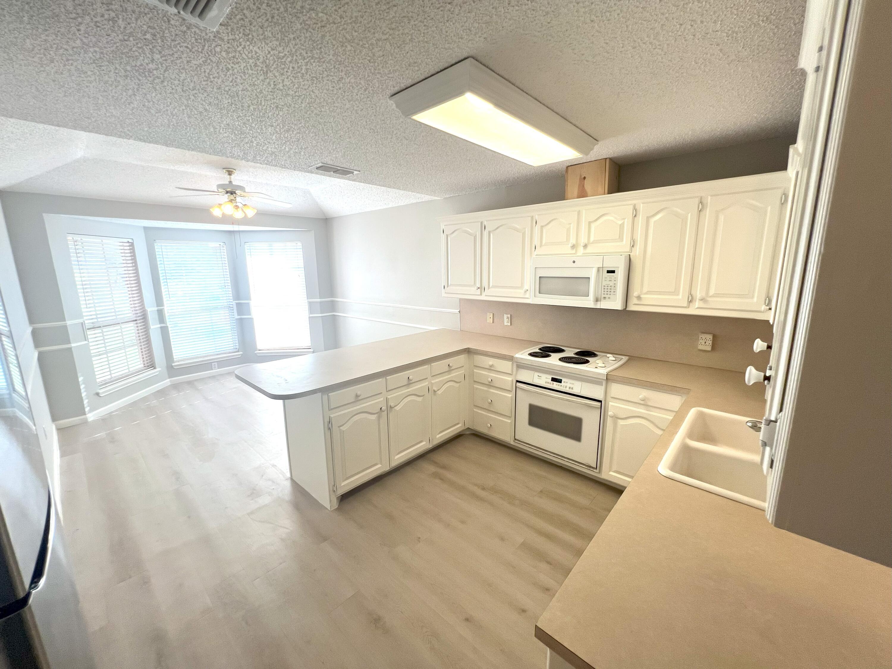 2314 Farm To Market 41 Lubbock, TX 79423 - Photo 10 of 18 a large white kitchen with stainless steel appliances granite countertop a stove a sink dishwasher and white cabinets with wooden floor