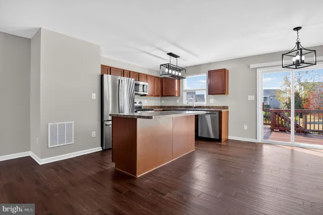 a kitchen with stainless steel appliances granite countertop a stove top oven a sink dishwasher and a refrigerator with wooden floor