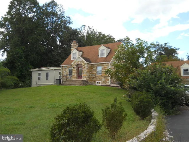a view of a house with a big yard potted plants and large tree