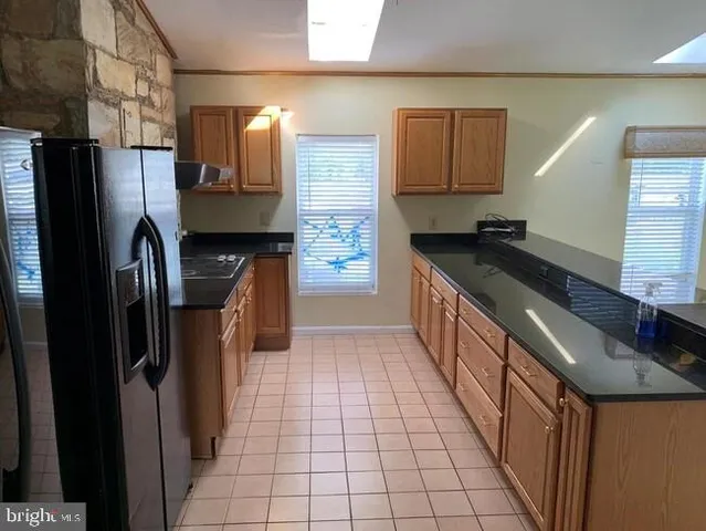 a kitchen with stainless steel appliances granite countertop a refrigerator a sink and wooden cabinets