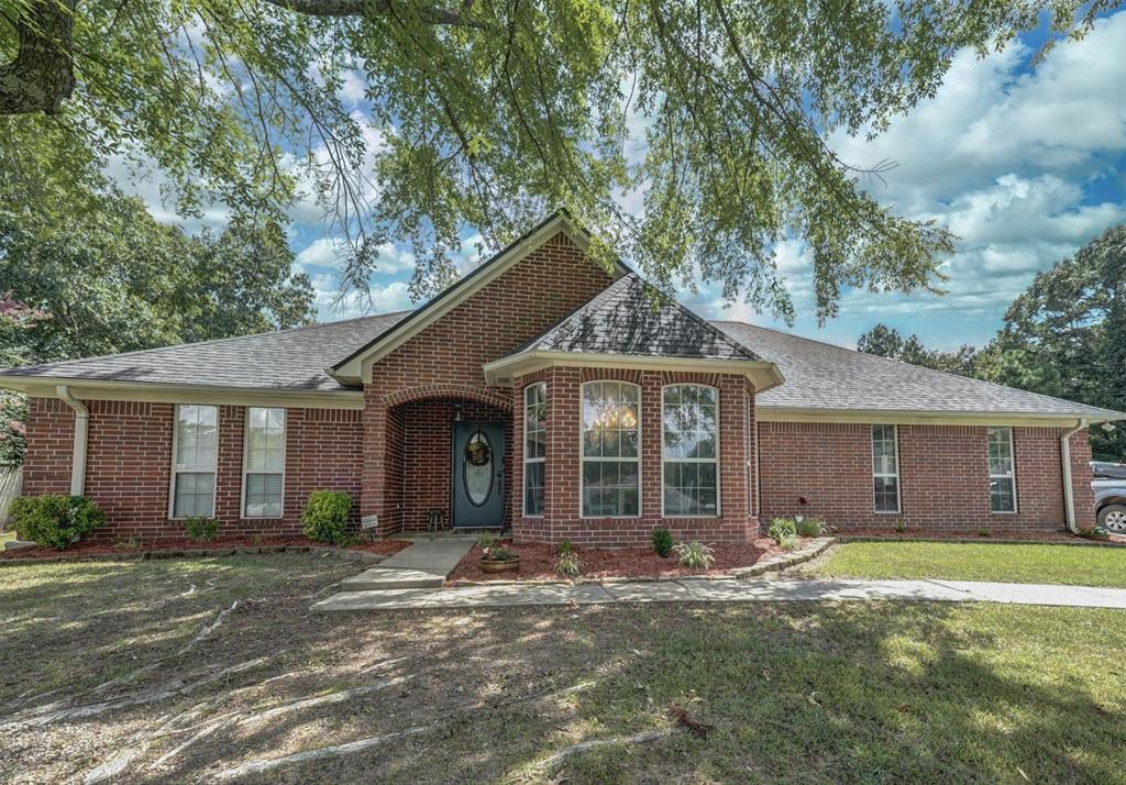 View of front of property featuring brick siding, a shingled roof, and a front yard
