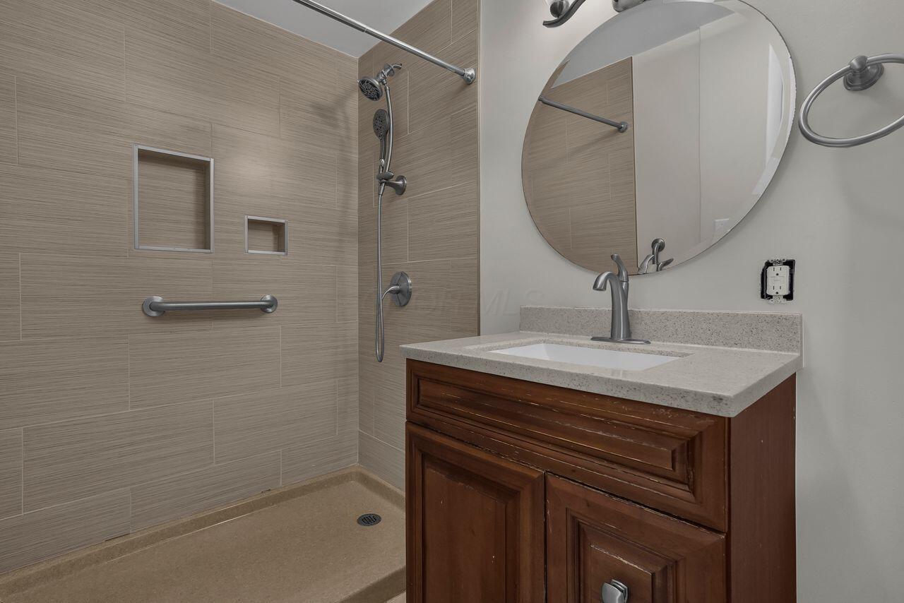 1535 Kenwick Road Columbus, OH 43209 - Photo 17 of 26 Ensuite bath with tiled walk-in shower, grab bars, and solid-surface vanity.