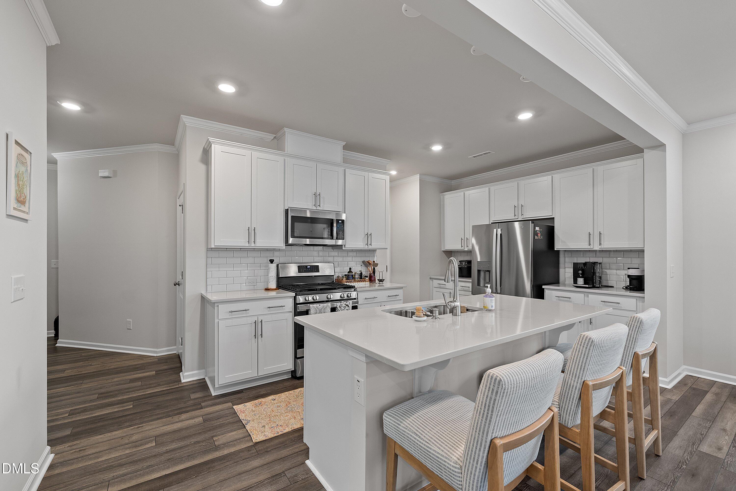 4028 Mount Moran Road Raleigh, NC 27616 - Photo 5 of 46 a kitchen that has a refrigerator a stove a sink and a dining table with wooden floor