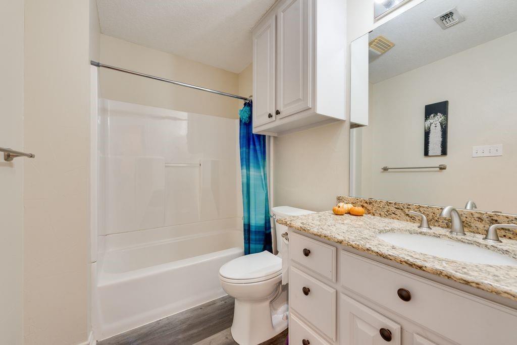 83 Crown Road Willow Park, TX 76087 - Photo 19 of 35 White vanity with dual integrated sinks, granite countertop, and brushed nickel fixtures