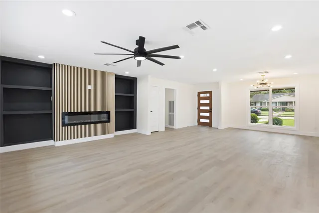 a view of an empty room with a window and a kitchen