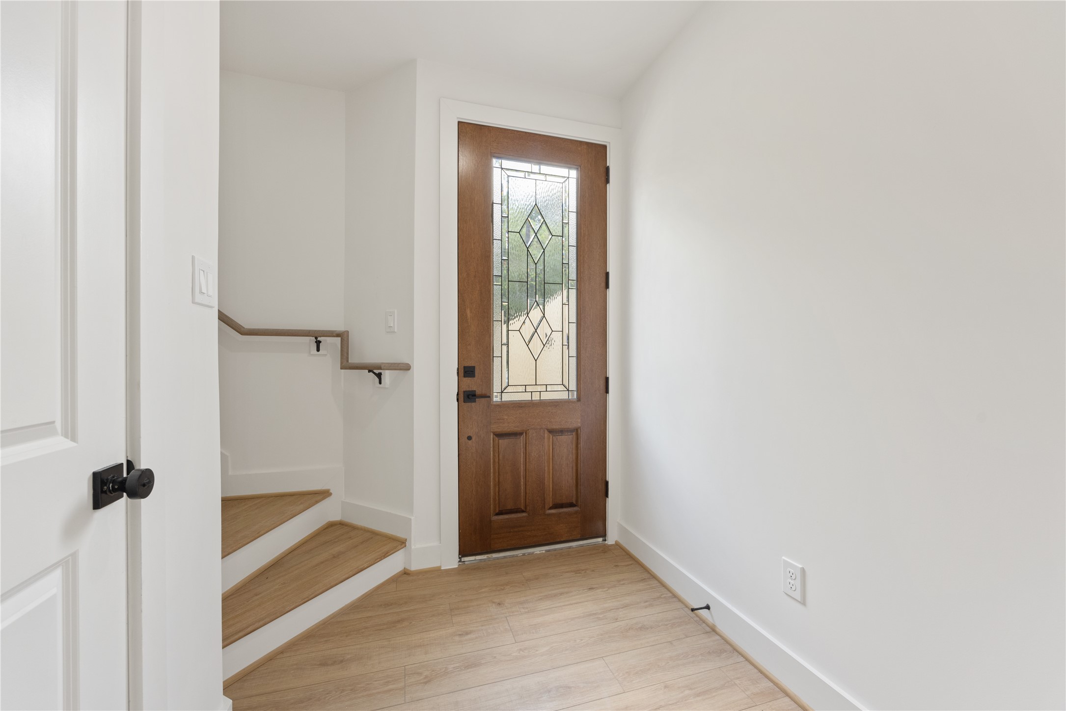2121 Hoskins Drive, Unit C Houston, TX 77080 - Photo 7 of 34 The foyer blends warmth and modern simplicity with a decorative glass front door, light flooring, white walls, and black accents. A nearby staircase leads to the main living level, while the entry area provides a polished, inviting transition into this thoughtfully designed new construction home.