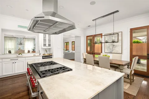 a kitchen with stainless steel appliances a stove a sink dishwasher and white cabinets with wooden floor