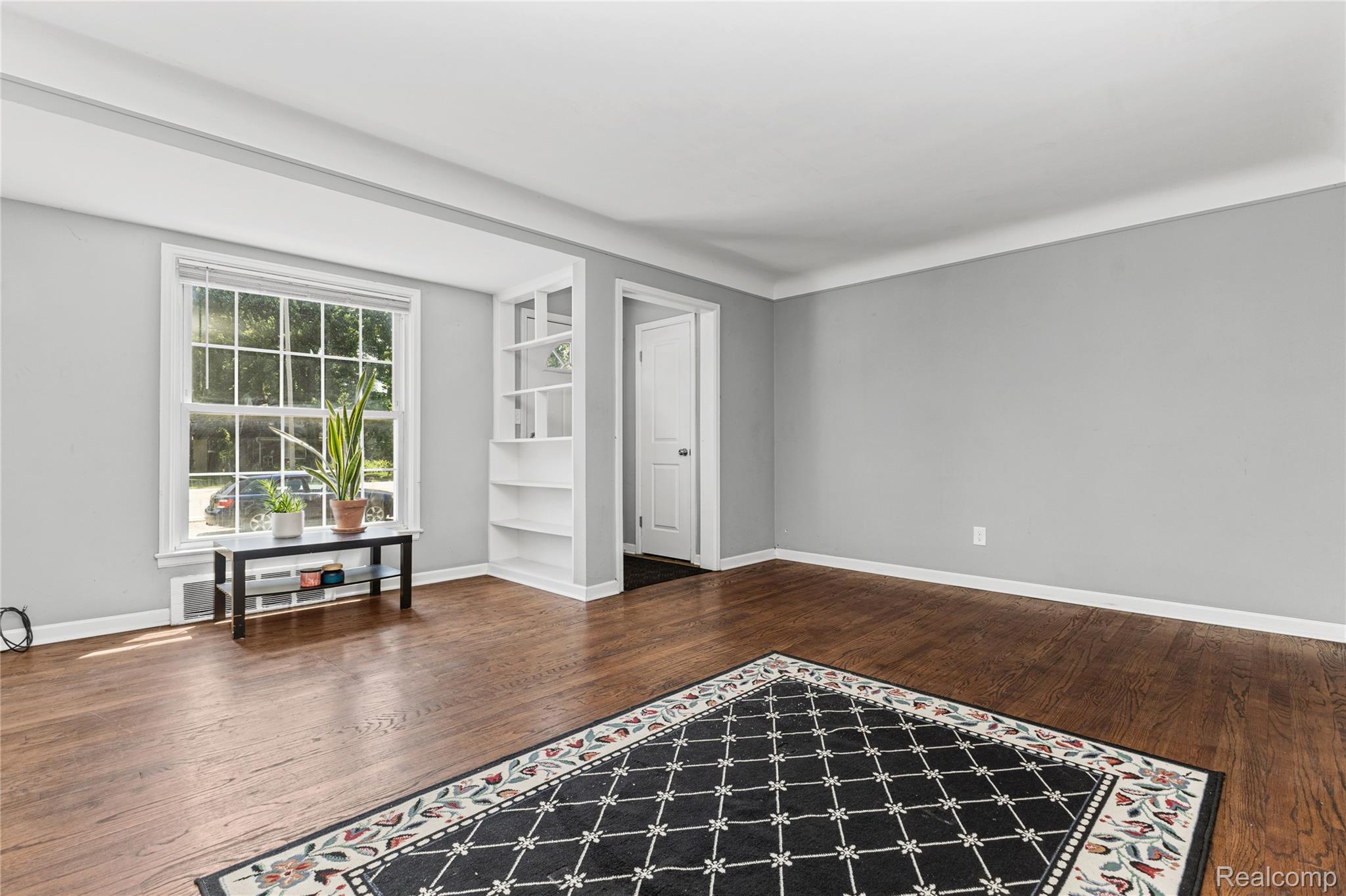 26508 Five Mile Road Redford, MI 48239 - Photo 9 of 41 Spacious room featuring wood-finish flooring, light grey walls, white trim, and a prominent window with grid panes