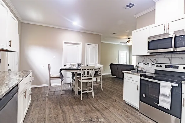a kitchen with stainless steel appliances a white table chairs and a stove