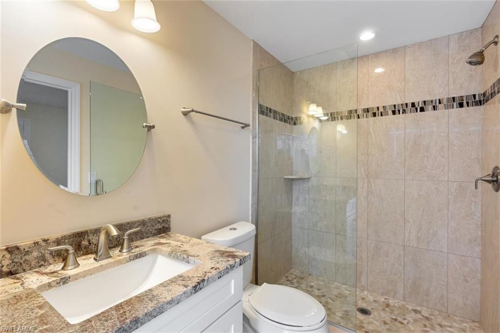 4851 Riverside Drive Estero, FL 33928 - Photo 20 of 35 a bathroom with a granite countertop sink mirror toilet and shower