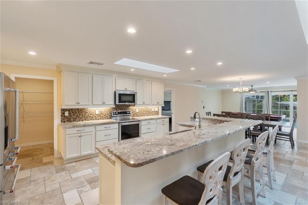 4851 Riverside Drive Estero, FL 33928 - Photo 6 of 35 a large kitchen with kitchen island a sink a stove a dining table and chairs