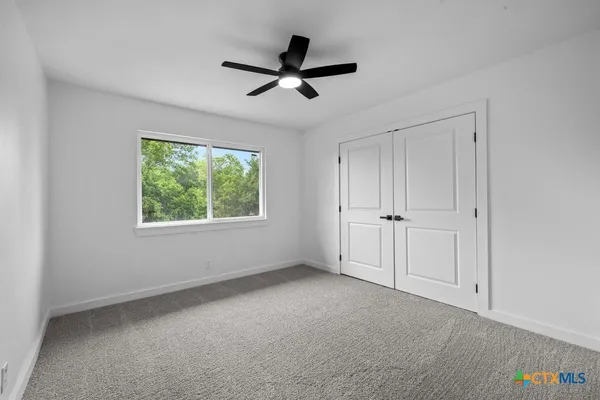 a view of empty room with window and ceiling fan