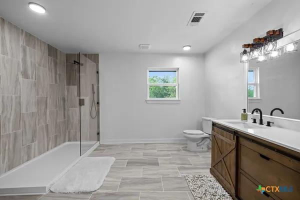 a bathroom with a sink a toilet and shower