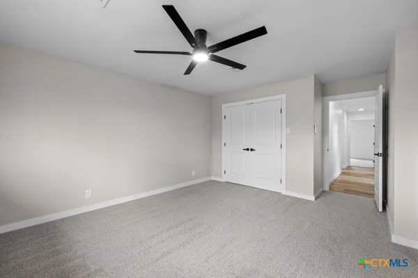 an empty room with a ceiling fan and wooden floor